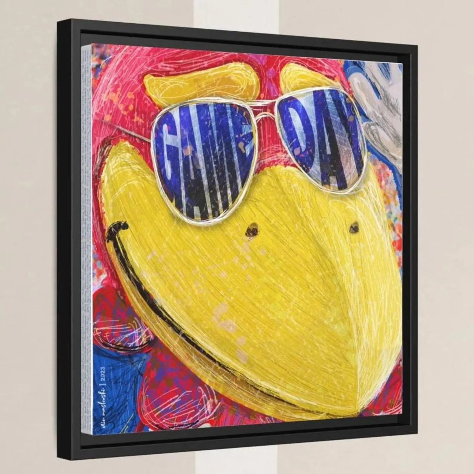 A framed artwork depicting a colorful, abstract bird wearing sunglasses with the text "GAME DAY" written on it.